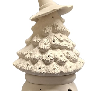 May include: White ceramic Christmas tree with a witch hat on top. The tree has a base with a moon and stars cut out.