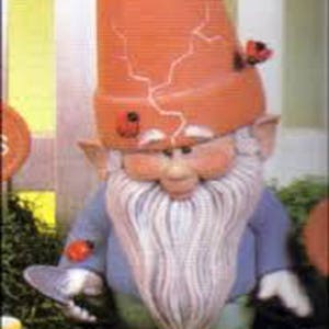 May include: A ceramic gnome figurine with a red hat, white beard, and blue shirt. The gnome is holding a small, round object in its hand. There are red ladybugs on the hat and shoes.