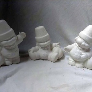May include: Three white ceramic figurines of people wearing hats and holding pumpkins. The figurines are in a standing position and are ready to be painted.