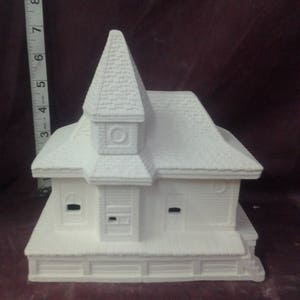 May include: White ceramic church building with a pointed roof and a small bell tower. The building has windows and a porch.
