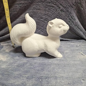 May include: A white ceramic squirrel figurine with a bushy tail. The squirrel is in a standing position with its head turned to the side.