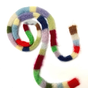 Peut inclure: Une écharpe tricotée multicolore en forme de spirale. L'écharpe est faite de fil doux et duveteux dans diverses couleurs, dont le rouge, le vert, le bleu et le violet. L'écharpe mesure environ 152 cm de long.