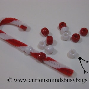 May include: A red and white candy cane made from pipe cleaners with white and red beads strung on it. There are additional beads scattered around the candy cane.