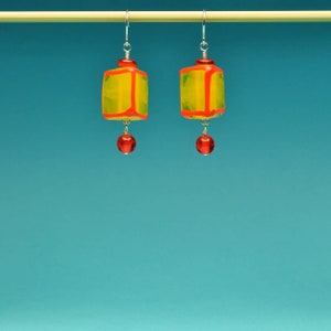 May include: A pair of yellow and red geometric glass earrings with red bead accents.
