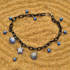 May include: A black chain necklace with blue glass beads and charms. The charms include two seashells and a starfish.