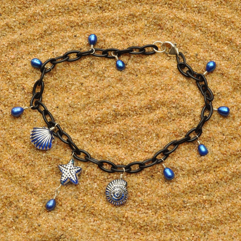May include: A black chain necklace with blue glass beads and charms. The charms include two seashells and a starfish.