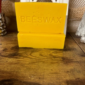 May include: Two rectangular blocks of yellow beeswax. The top block has the word "BEESWAX" embossed on the front.