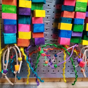 May include: Two colorful wooden toy bird perches with multi-colored wooden blocks and leather straps with colorful strings and beads.
