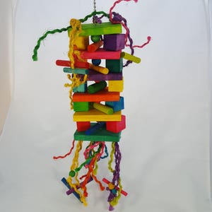 May include: A colorful wooden bird toy with a variety of shapes and sizes. The toy is suspended from a string and has a variety of colorful ropes hanging from it.