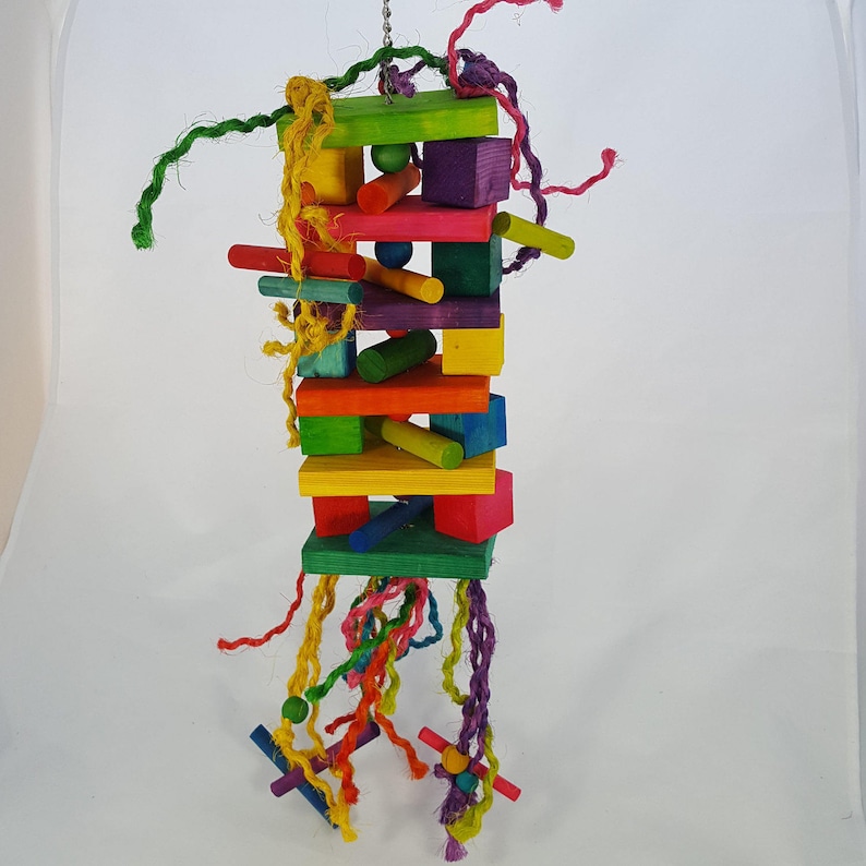 May include: A colorful wooden bird toy with a variety of shapes and sizes. The toy is suspended from a string and has a variety of colorful ropes hanging from it.