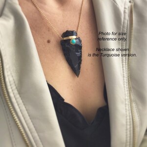 Op de afbeelding: Een zwarte obsidianen pijlpunt hangerketting met een turquoise steentje accent. De ketting is aan een gouden ketting en wordt door een persoon gedragen. Foto ter grootte-referentie alleen. De getoonde ketting is de turquoise versie.