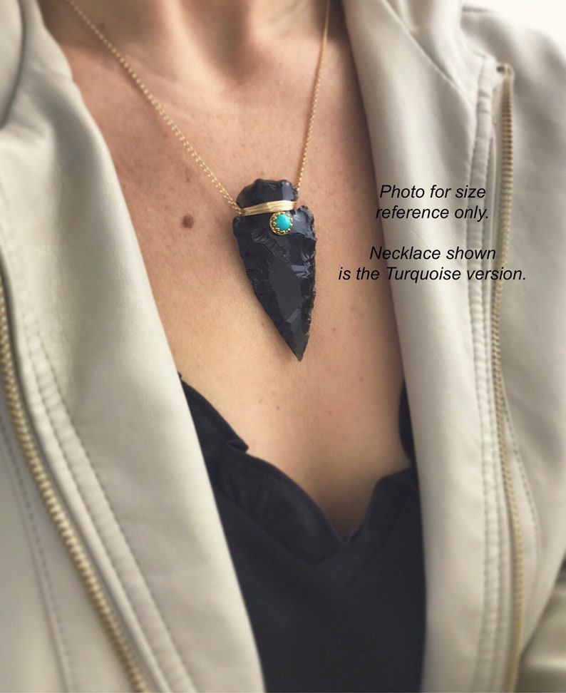 Op de afbeelding: Een zwarte obsidianen pijlpunt hangerketting met een turquoise steentje accent. De ketting is aan een gouden ketting en wordt door een persoon gedragen. Foto ter grootte-referentie alleen. De getoonde ketting is de turquoise versie.