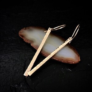 May include: A pair of gold hammered bar earrings with a simple hook closure.