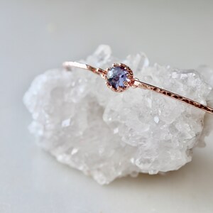 Pode incluir: Um delicado bracelete de ouro rosa com uma pequena gema redonda de cor p&uacute;rpura engastada.