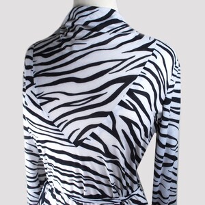 May include: A long-sleeved white and black zebra print robe with a wrap style closure and a tie belt.