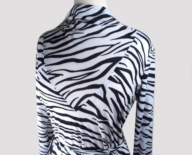May include: A long-sleeved white and black zebra print robe with a wrap style closure and a tie belt.