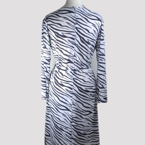 May include: A white and black zebra print long-sleeved dress with a tie at the waist.