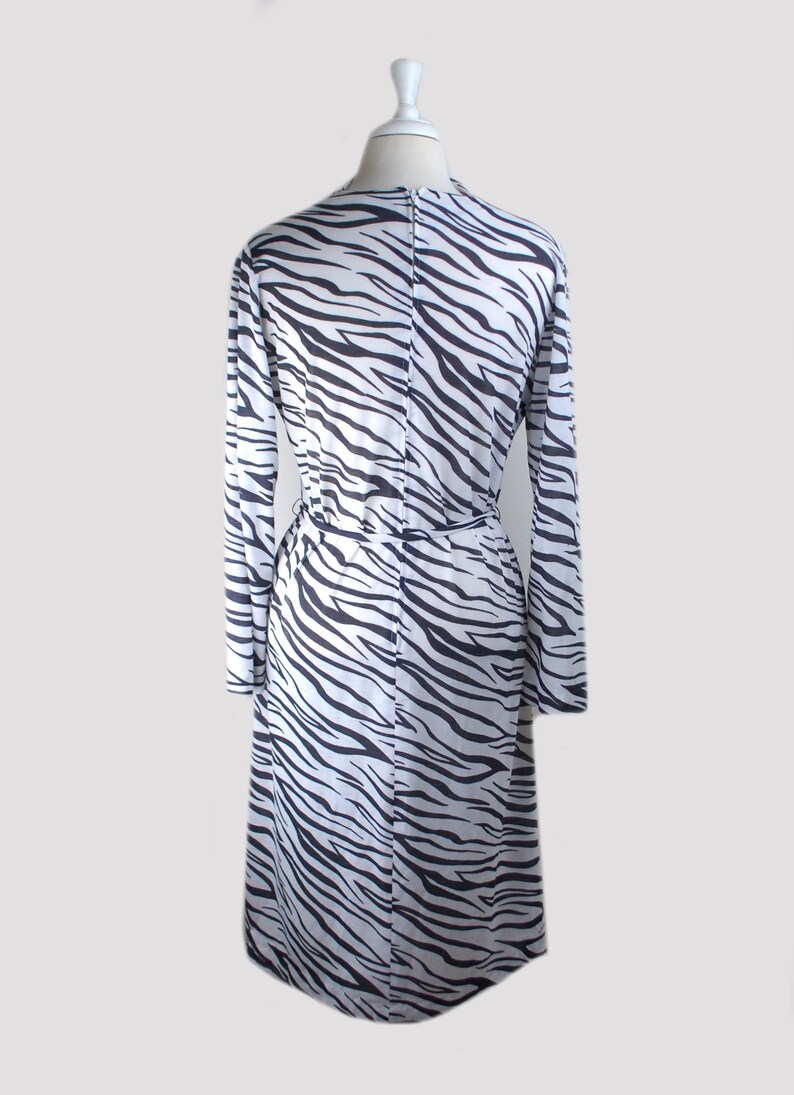May include: A white and black zebra print long-sleeved dress with a tie at the waist.