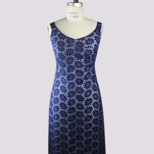 May include: A navy blue sleeveless dress with a white floral pattern. The dress is on a mannequin.
