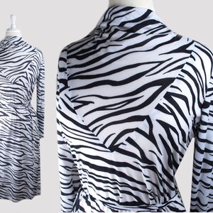 May include: A white and black zebra print long-sleeved wrap dress with a tie belt.