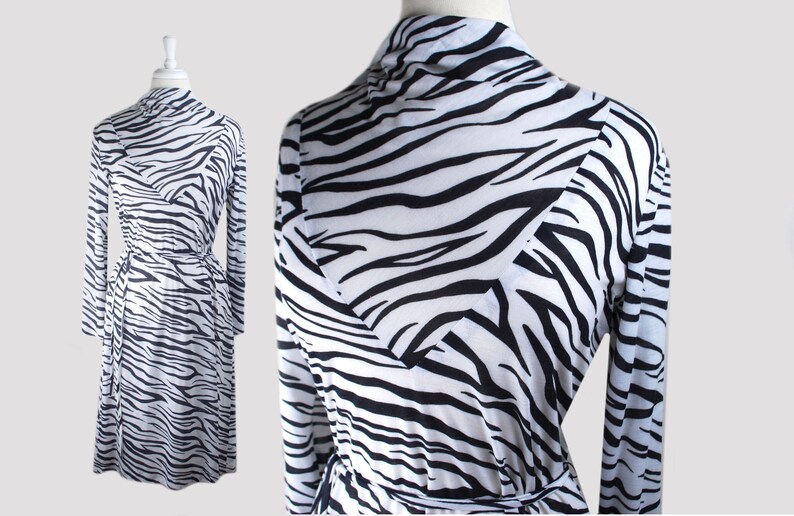 May include: A white and black zebra print long-sleeved wrap dress with a tie belt.