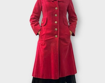 May include: A long, pink velvet coat with a flared skirt and silver buttons. The coat has two large pockets on the front.