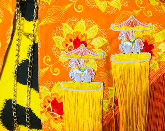 Cute orange caplet with tiny carousel motifs and long fringing