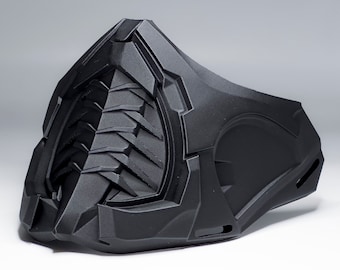 May include: A black, futuristic-style mask with a textured surface. The mask features angular designs and a central, ridged section. The overall aesthetic suggests a sci-fi or cosplay theme.