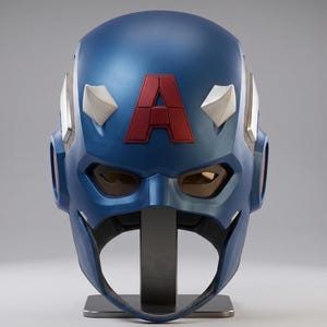 May include: A blue Captain America helmet with a red "A" emblem. The helmet features white accents and a visor. It is displayed on a black stand against a gray background. The helmet is a replica of the one worn by the superhero.