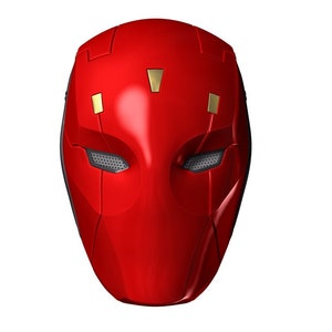 以下が含まれることがあります： 幾何学的なデザインの赤と金のスーパーヒーローマスク。マスクには目の穴が2つと尖ったあごがあります。