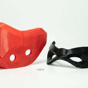 Peut inclure: Deux masques imprim&eacute;s en 3D, l'un rouge et l'autre noir. Le masque rouge est plus grand et comporte deux trous. Le masque noir est plus petit et a une forme de masque pour les yeux plus traditionnelle.