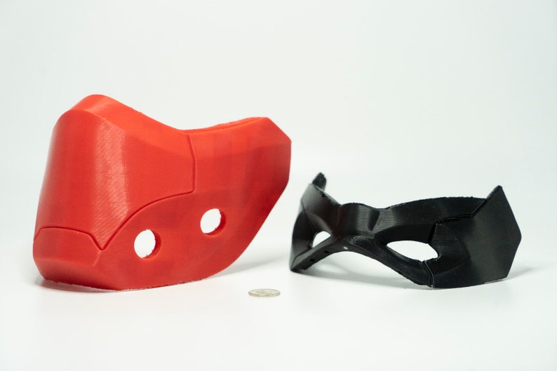 Peut inclure: Deux masques imprim&eacute;s en 3D, l'un rouge et l'autre noir. Le masque rouge est plus grand et comporte deux trous. Le masque noir est plus petit et a une forme de masque pour les yeux plus traditionnelle.