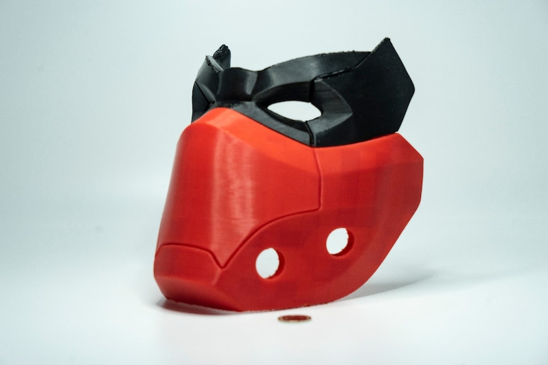 Peut inclure: Un masque imprim&eacute; en 3D rouge et noir avec un design g&eacute;om&eacute;trique. Le masque a deux trous sur le c&ocirc;t&eacute; et une cr&ecirc;te sur&eacute;lev&eacute;e sur le dessus.