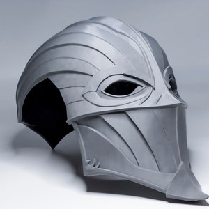 May include: A gray, 3D printed helmet with a pointed, beak-like nose and eye holes. The helmet has a textured, layered design.