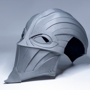 May include: A gray 3D printed helmet with a visor and a pointed chin guard. The helmet has a textured surface and a design that resembles a bird's beak.