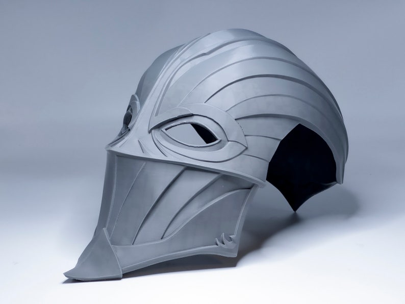 May include: A gray 3D printed helmet with a visor and a pointed chin guard. The helmet has a textured surface and a design that resembles a bird's beak.