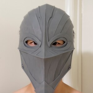 May include: A gray 3D printed helmet with a detailed design and eye holes.