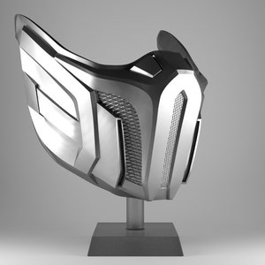 May include: A silver-colored mask with a geometric design. The mask is on a black stand.
