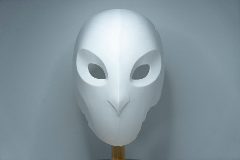 Op de afbeelding: Een wit uilenmasker met grote oogopeningen en een puntige snavel. Het masker is gemaakt van een glad, stevig materiaal en is ontworpen om op het gezicht te worden gedragen. Het masker is een kostuumaccessoire.