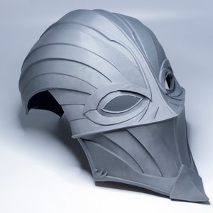 May include: A gray, 3D printed helmet with a stylized, bird-like design. The helmet has a pointed beak and two eye holes.