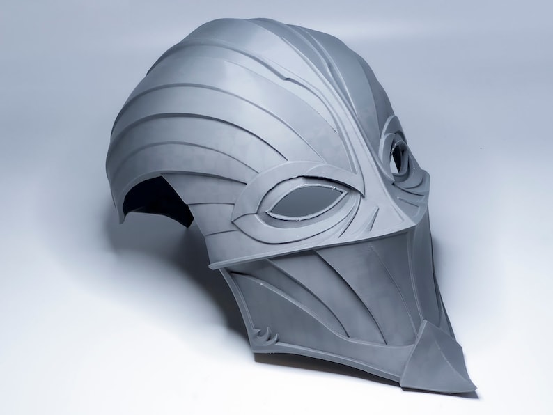 May include: A gray, 3D printed helmet with a stylized, bird-like design. The helmet has a pointed beak and two eye holes.