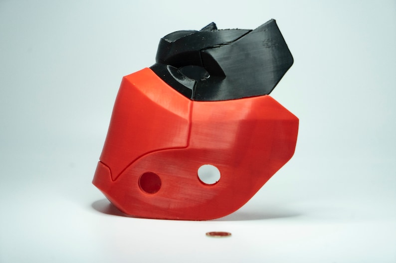 Peut inclure: Un masque rouge et noir imprim&eacute; en 3D avec un design g&eacute;om&eacute;trique. Le masque a deux trous sur le c&ocirc;t&eacute; et un petit trou sur le dessus.
