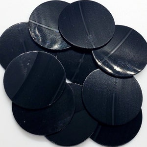 May include: A pile of ten black round sequins, each with a subtle sheen.