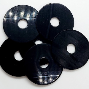 May include: Five black plastic washers with a center hole. The washers have a slightly textured surface.