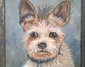 May include: An oil painting of a small dog with brown and white fur, wearing a blue collar with a tag. The painting is framed in a gray wooden frame. The painting is titled "Traveler" and signed by Susan Barockman.
