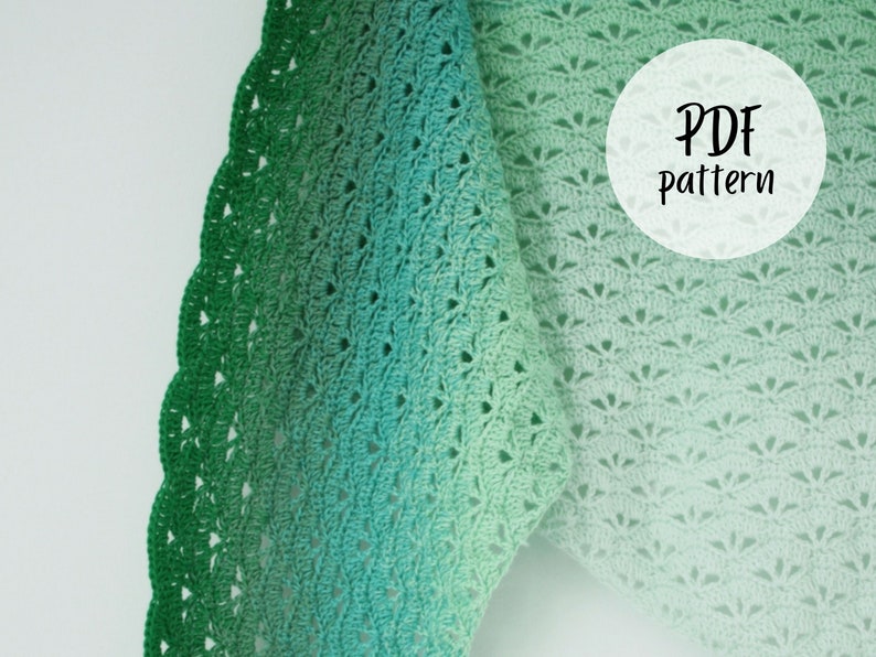 May include: A crochet shawl with a green ombre color gradient. The shawl has a delicate lace pattern and a scalloped edge. The text "PDF Pattern" is written on a white circle in the upper right corner of the image.