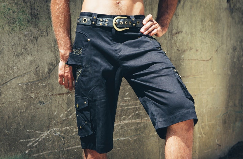 May include: Black cargo shorts with a leather belt and gold accents. The shorts have multiple pockets and a mesh panel on the side.