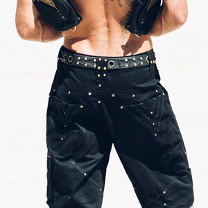 May include: Black cargo shorts with a studded belt and two black leather bags worn as a harness.