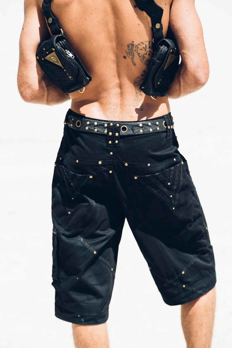 May include: Black cargo shorts with a studded belt and two black leather bags worn as a harness.