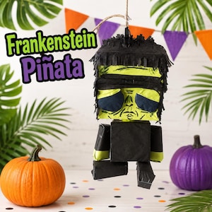 May include: A Frankenstein piñata featuring a lime green face with black hair, dark eyes, and a black torso. The text Frankenstein Piñata is printed in green and purple letters. The figure is suspended by a string and has a blocky, square-shaped design.